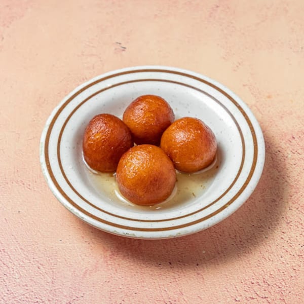 Four golden-brown gulab jamun soaked in syrup, served in a white bowl with brown stripes.