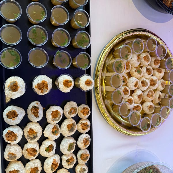 Pani Puri, an Indian street food, with small cups of spiced water and hollow crispy shells.