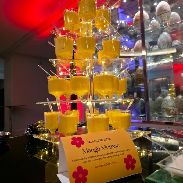 Mango Mousse desserts on a tiered stand with a "Passage to India" sign.