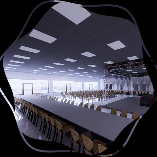 A large, modern event space with long tables, chairs, and a stage with lighting trusses.