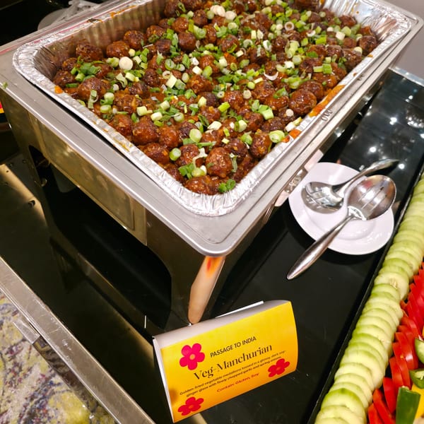 Veg-Manchurian in a chafing dish, garnished with green onions, at Passage to India restaurant.