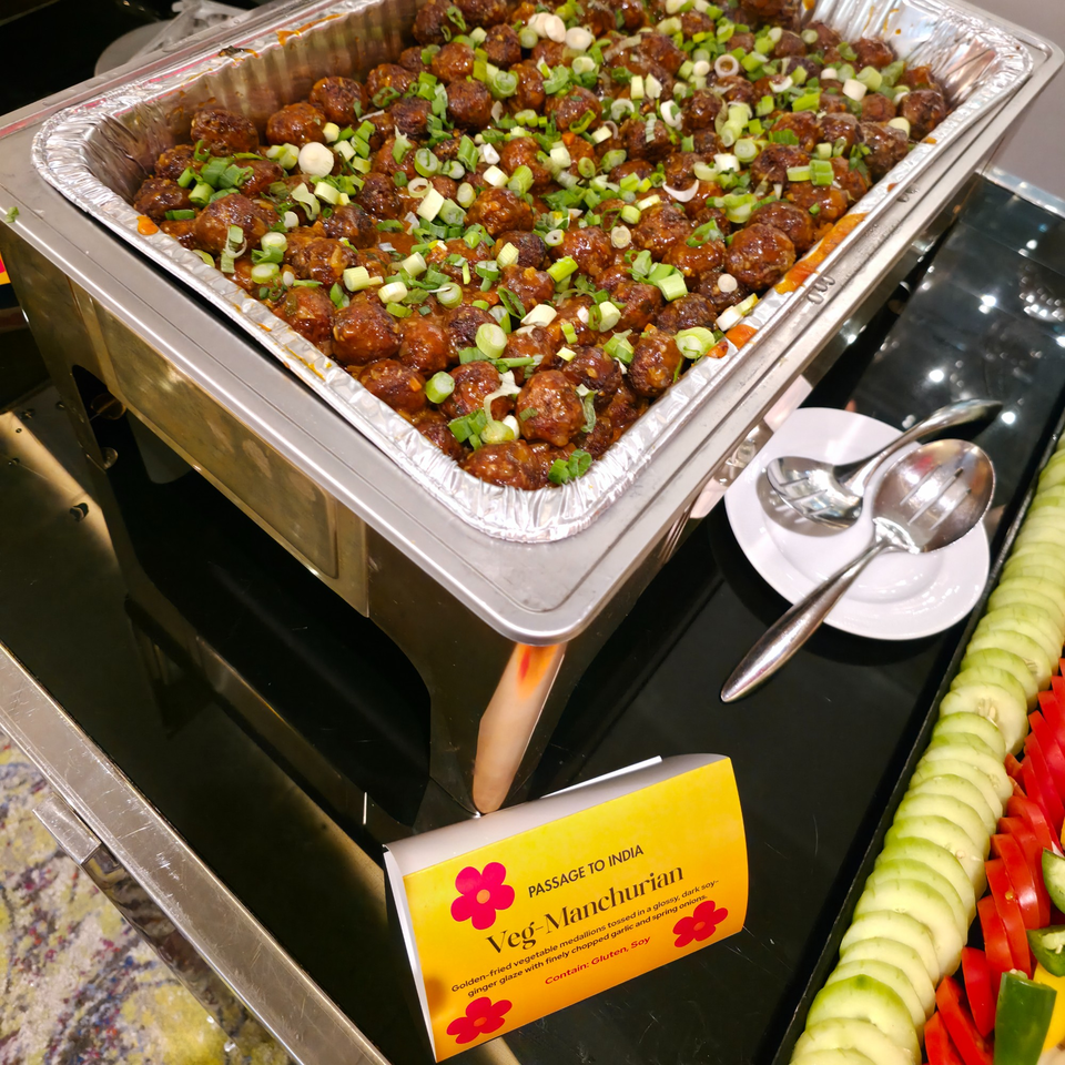 Veg-Manchurian in a chafing dish, garnished with green onions, at Passage to India restaurant.