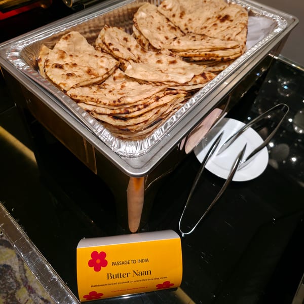 A chafing dish filled with golden-brown Butter Naan, with serving tongs and a label for "Passage to India".