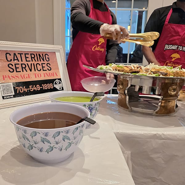 Passage To India catering staff serving Indian food from a chafing dish with sauces.