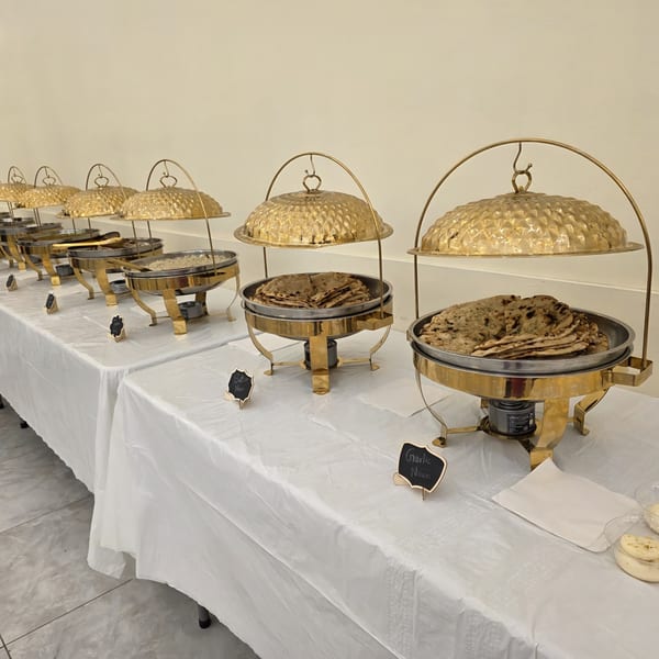 A buffet line of golden chafing dishes filled with Indian naan bread and rice.
